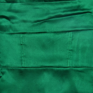 Vue détaillée du tissu en soie vert émeraude avec des coutures piquées de qualité