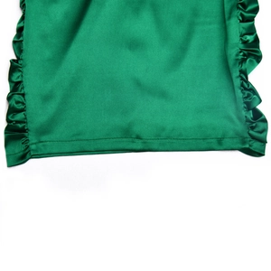 Détail de l'ourlet de la robe en satin vert foncé avec d'élégants bords à volants
