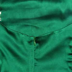Détail d'une fermeture éclair invisible sur une robe moulante en satin vert émeraude soyeux