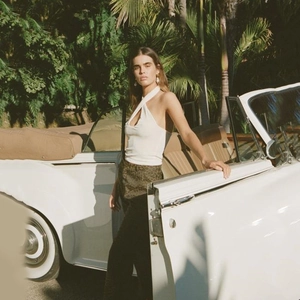 Detail shot of a white halter neck top paired with leopard print trousers outdoors