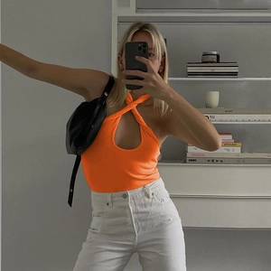 Detail showing bright orange halter top with front twist design and teardrop cutout