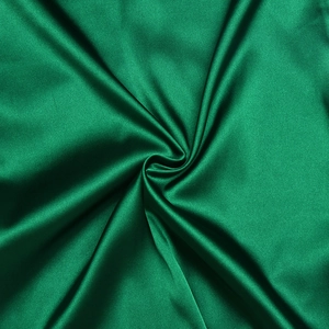 Détail du tissu en satin vert foncé montrant une texture lisse et un éclat soyeux luxe