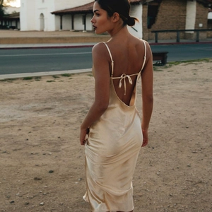 Close-up of elegant champagne satin dress featuring backless V-cut and bow tie details