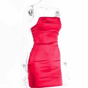 Détail de robe moulante en satin rouge montrant des fronces latérales et un tissu brillant