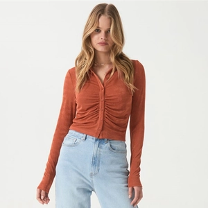 Detail of long sleeve knit top with ruched front and polo collar in caramel orange