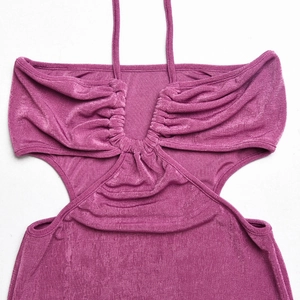 Détail de robe en maille fuchsia avec licou, plis à la poitrine et découpes à la taille