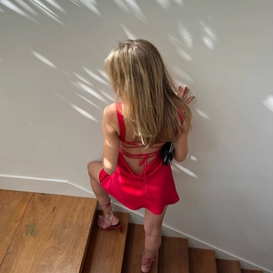 Detail of red satin backless dress with crisscross straps and silky texture finish