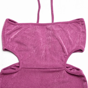Détail de la robe licou fuchsia avec tissu à texture métallique et découpes à la taille