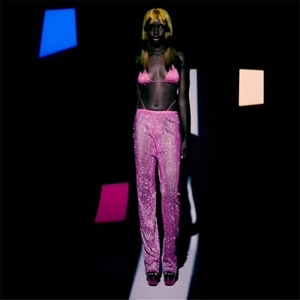 Détail du pantalon large en mesh rose à strass et haut de bikini sous lumière de studio