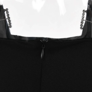 Close-up of black dress fabric with silver metal chains and invisible zipper detail