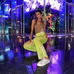 Gros plan sur le pantalon à paillettes vert fluo pour femme avec une coupe large style