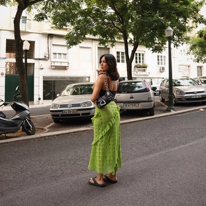 Bright green lace maxi skirt with ruffle details shown in a stylish outdoor street setting