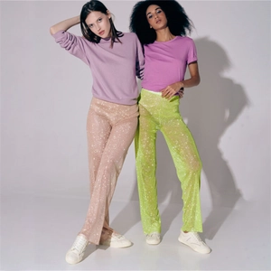 Détail de pantalons larges à paillettes taille haute en rose et vert fluo brillants