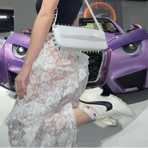 Detailed view of white faux leather bag with sharp silver studs and lace skirt texture