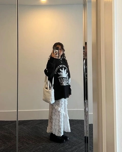 Detail of a white lace tiered maxi skirt styled with a black streetwear sweatshirt