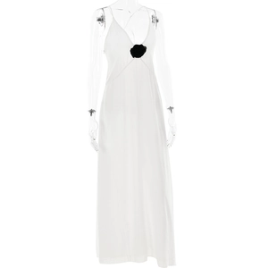 Detail of elegant white chiffon maxi dress with black 3D floral accent on V-neckline