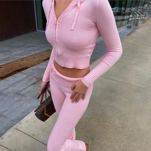 Outdoor street view of pink knitted two-piece set with hooded top and flared pants