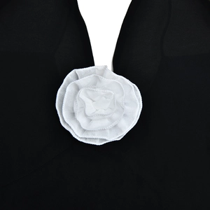 Close-up of white chiffon flower accessory on a black V-neck dress detail