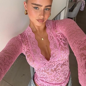 Top sexy in pizzo rosa con scollo a V e maniche a campana per un look audace e trendy.
