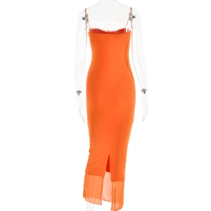Détail d'une robe longue orange avec dentelle rouge et fente en tulle transparent au bas
