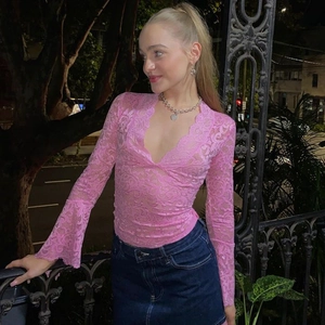 Dettaglio del top in pizzo rosa con profondo scollo a V ed eleganti maniche a campana