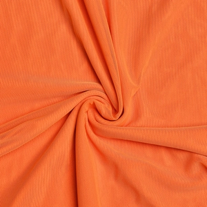 Vue macro détaillée du tissu en maille orange vif avec drapé en spirale et texture fine