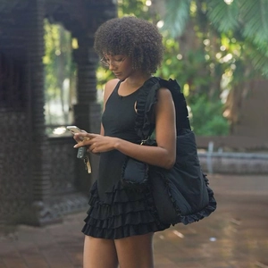 Robe courte noire sans manches à volants superposés avec un grand sac porté épaule chic