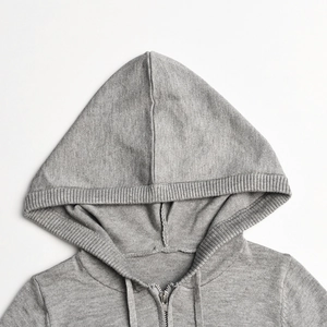 Detail of grey knitted hoodie showing metal zipper, drawstring, and soft fabric texture