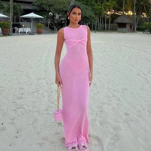 Robe longue rose sans manches en maille avec détail torsadé sur un fond de plage ensoleillé