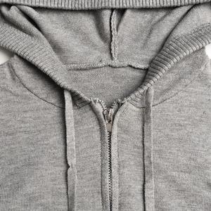 Detail of grey knitted hoodie showing smooth silver metal zipper and woven drawstring