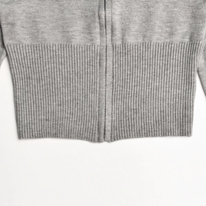 Detail view of gray knitted top with silver metal zipper and ribbed hemline texture