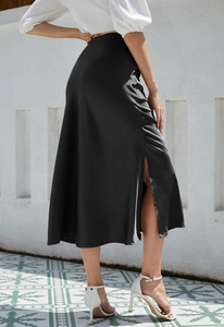 Detail view of high side slit on black satin midi skirt showing elegant drape and texture