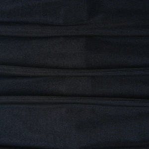 Détail du tissu en maille noire montrant la texture tricotée et les plis horizontaux
