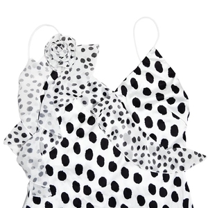 Detailed view of white satin dress with black polka dots and 3D flower strap detail