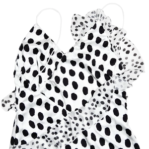 Detail of white satin dress featuring black polka dots and delicate ruffle textures