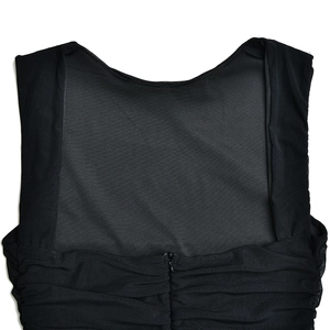 Vue macro de l'encolure de robe noire avec empiècement en maille, plis et zip caché