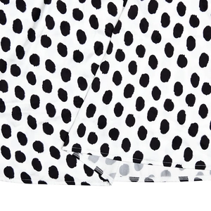 Close-up of white satin dress featuring black polka dots and high-quality flatlock stitching