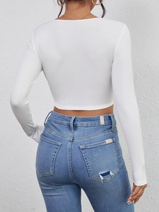 Rear view of white ribbed knit crop top and distressed blue jeans on a model