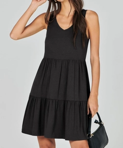 Detail of a black V-neck tiered sleeveless dress showing knit texture and layered hem