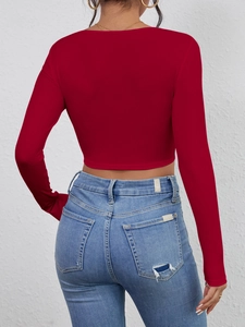 Rear view of red ribbed long sleeve crop top paired with distressed blue skinny jeans