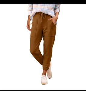 Dettaglio dei pantaloni cargo marrone caramello con coulisse in vita e grandi tasche utility