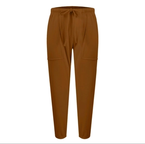 Dettaglio dei pantaloni sportivi color caramello con coulisse e grandi tasche applicate