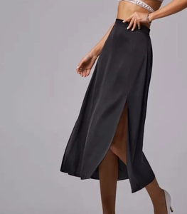 Close-up of sleek black satin midi skirt featuring a high side slit and smooth finish