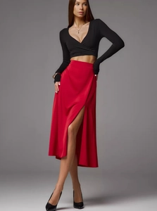 Detail of red satin skirt with high side slit and smooth texture on a model