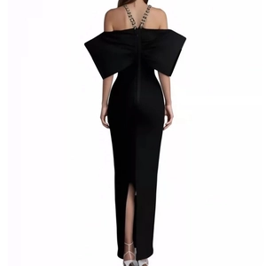 Detail view of a large decorative bow and elegant back slit on this black evening dress