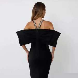 Detail view of a black bodycon dress featuring a large back bow and rhinestone straps
