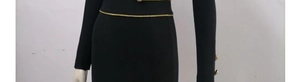 Detail of gold chain belt and embossed buttons on a black bandage long sleeve dress