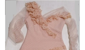 Detail of pink mesh bodysuit with white polka dots and delicate lace ruffles on neck