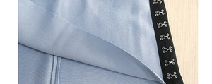 Détail d'une robe en maille bleu clair avec fermetures à agrafes noires sur tissu côtelé