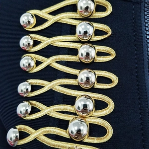 Macro detail of silver spherical buttons and golden braided embroidery on knit jacket